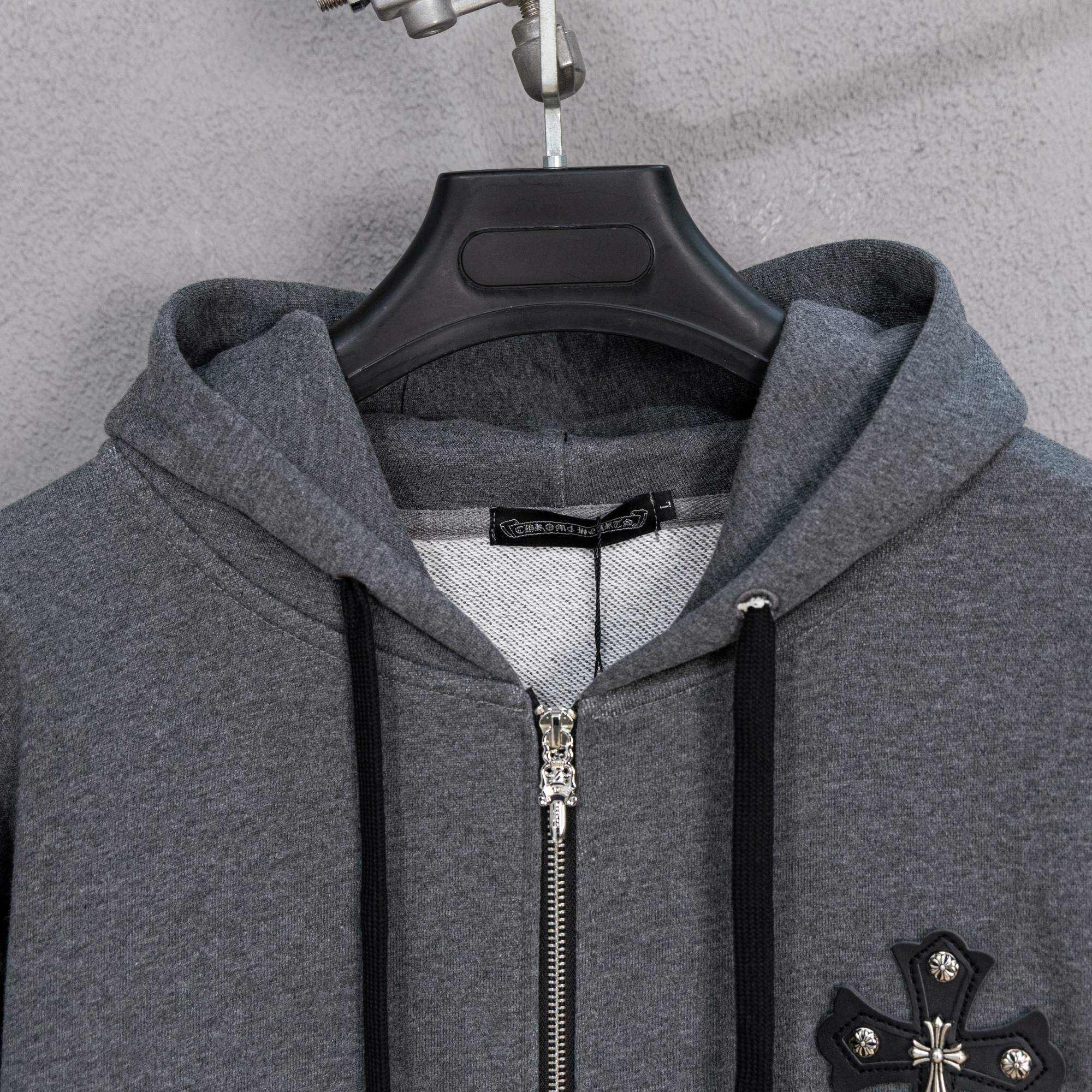 Grey hooded zip-up jacket with silver zipper and cross chest detail