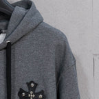 Grey hoodie side view with black cross appliqué on left chest
