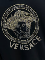 Black crewneck sweatshirt front with gold rhinestone Medusa logo and Versace text