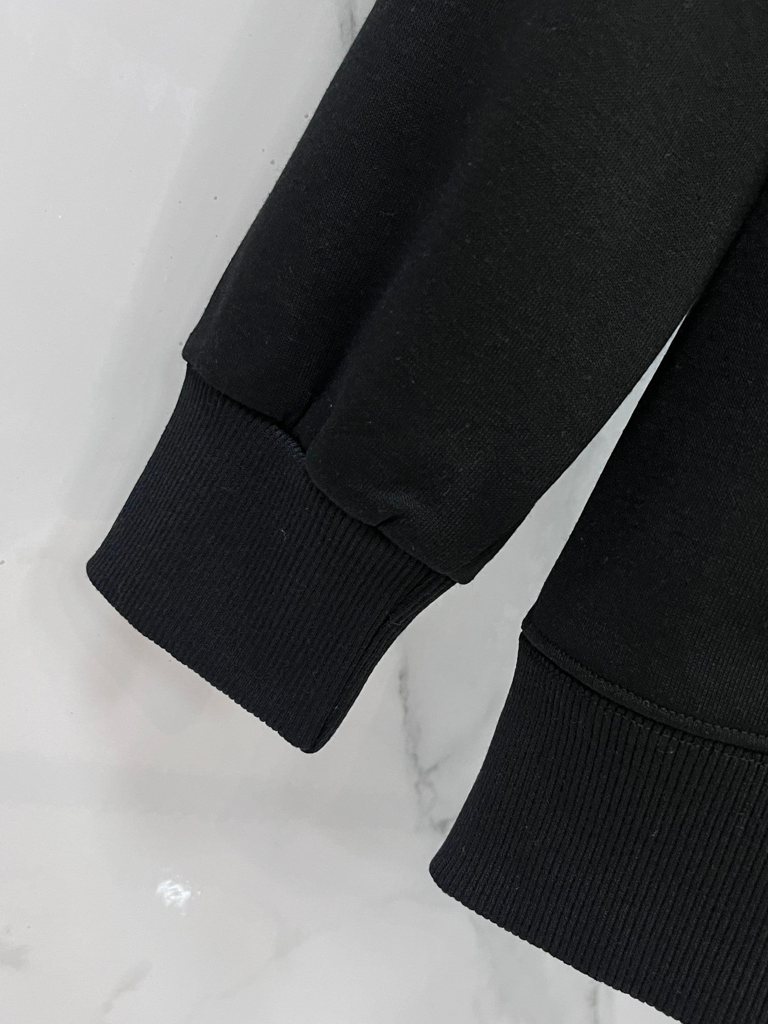Black crewneck sweatshirt sleeve and ribbed cuff detail