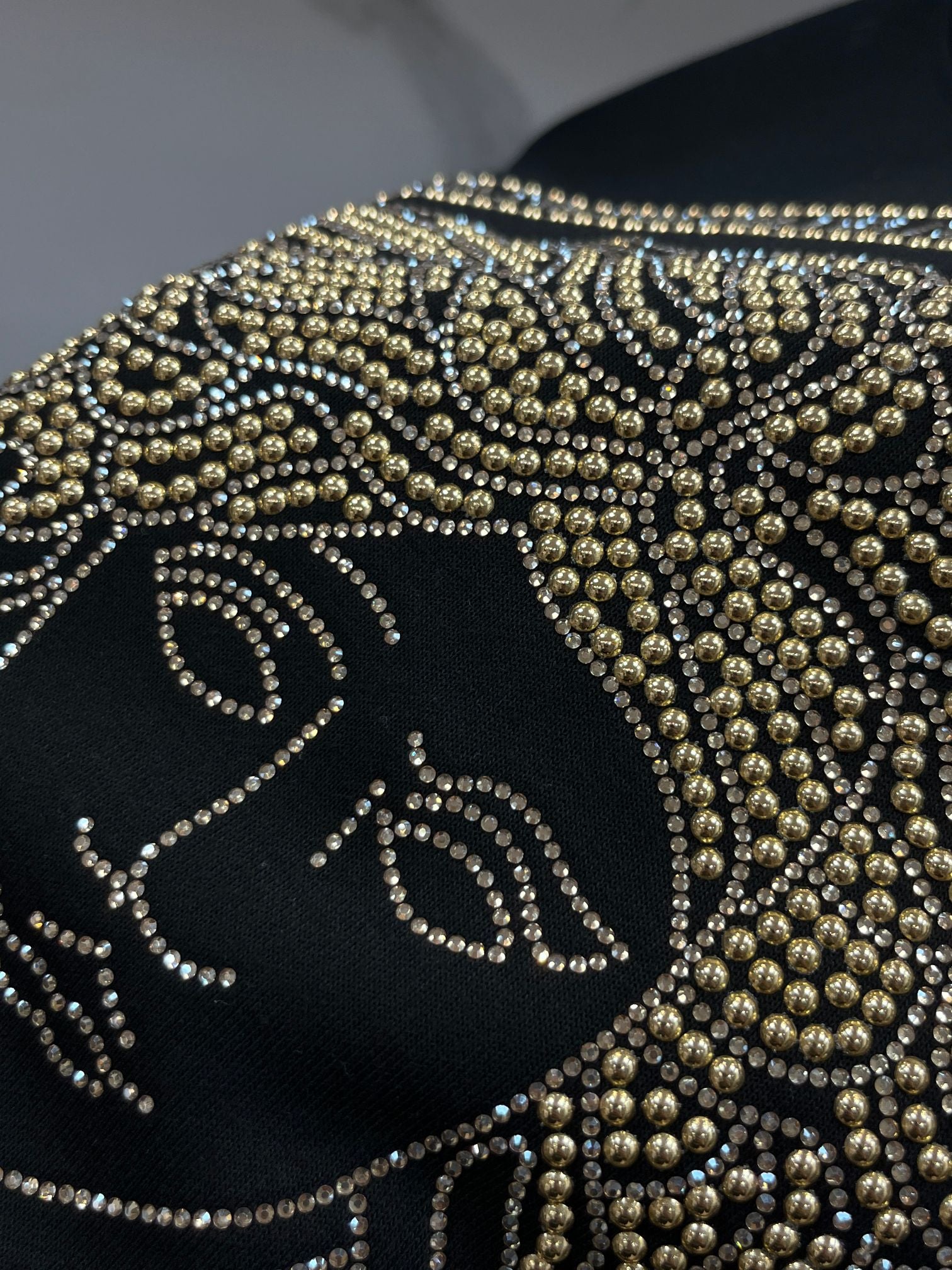 Black crewneck sweatshirt front detail with gold rhinestone face motif