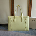 Light yellow-green leather tote bag with curved top handles and front logo stamp