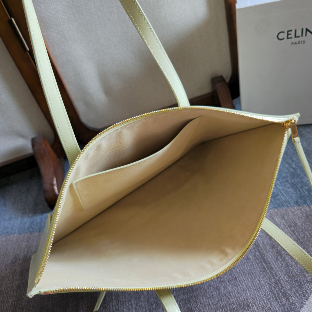 Light yellow-green leather tote bag with open interior and gold zipper trim