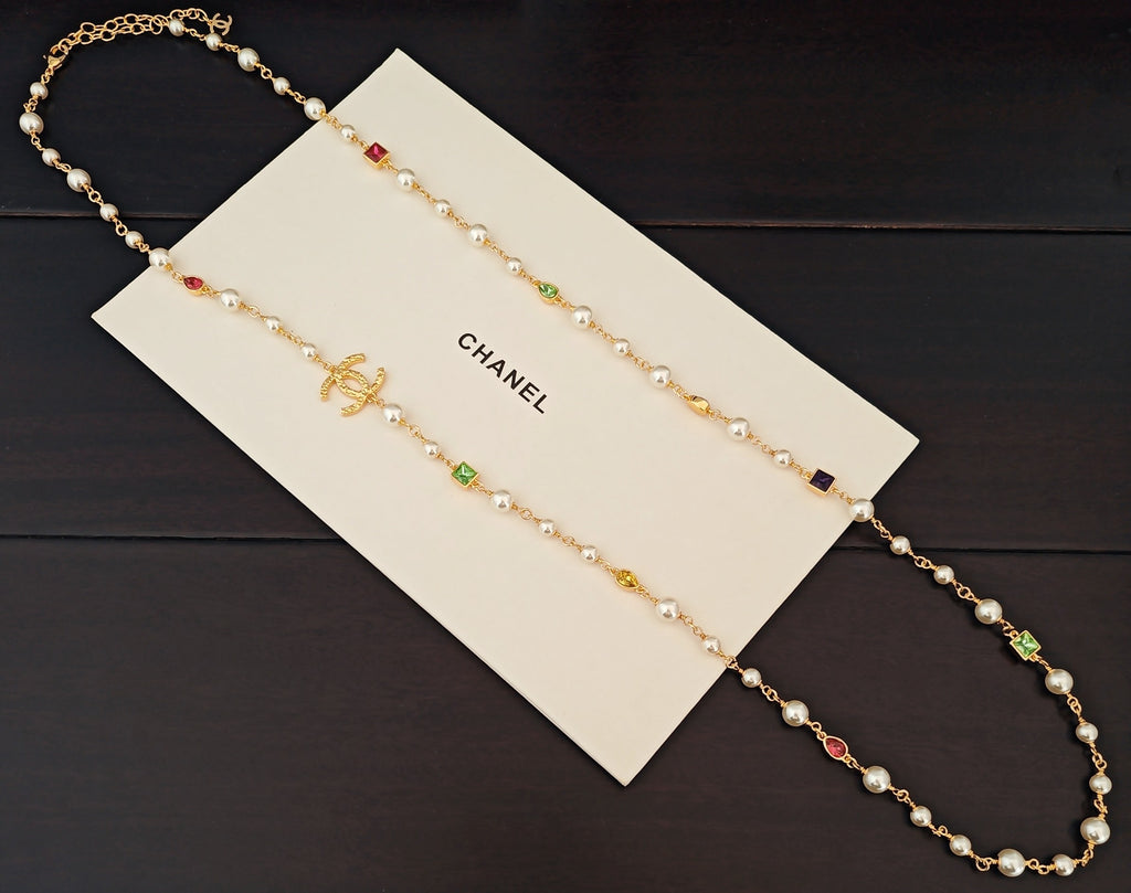 Gold-tone beaded necklace with pearl-like beads and green, red, and blue crystal charms
