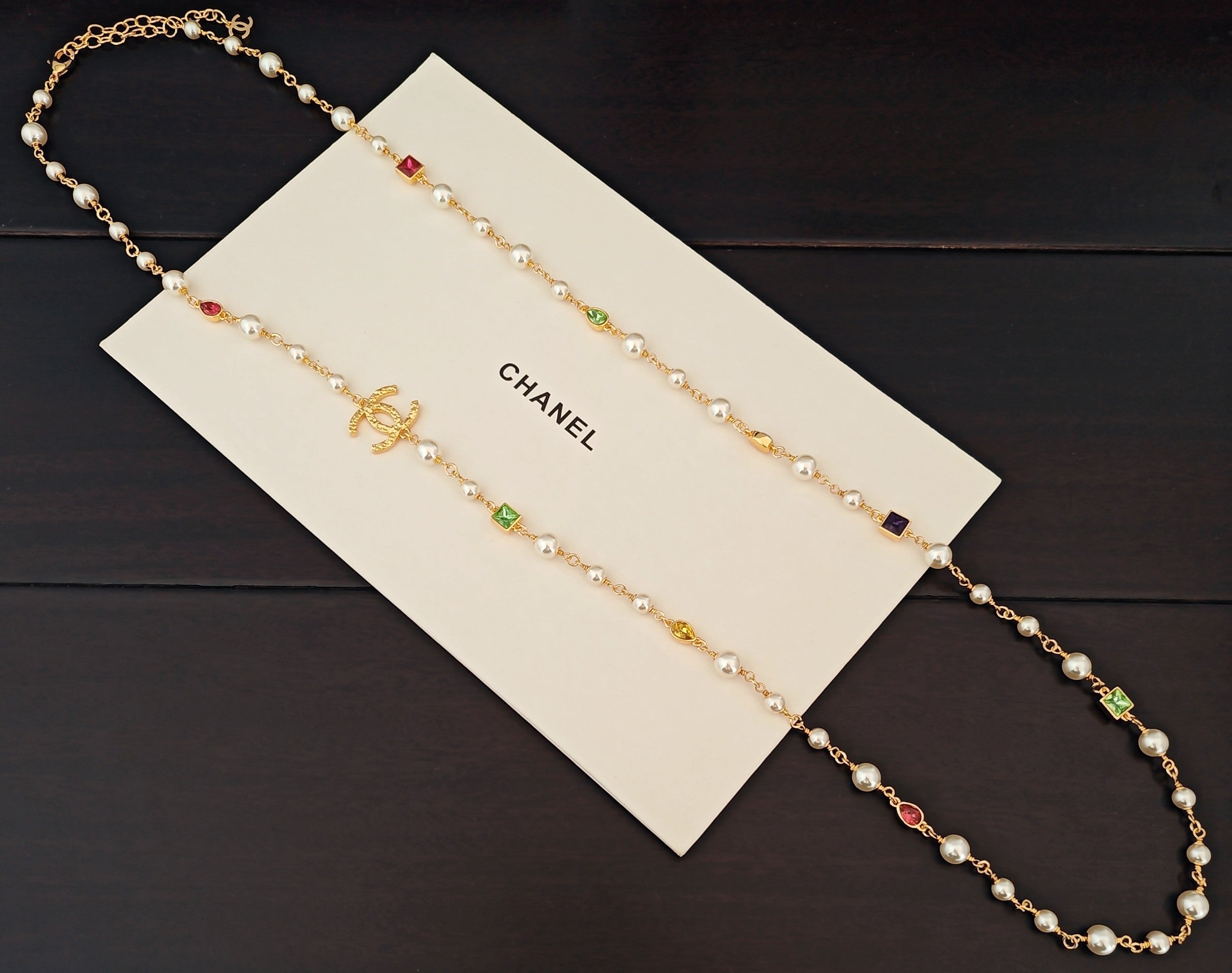 Gold-tone beaded necklace with pearl-like beads and green, red, and blue crystal charms