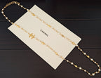 Gold-tone beaded necklace with pearl-like beads and small logo charm accents
