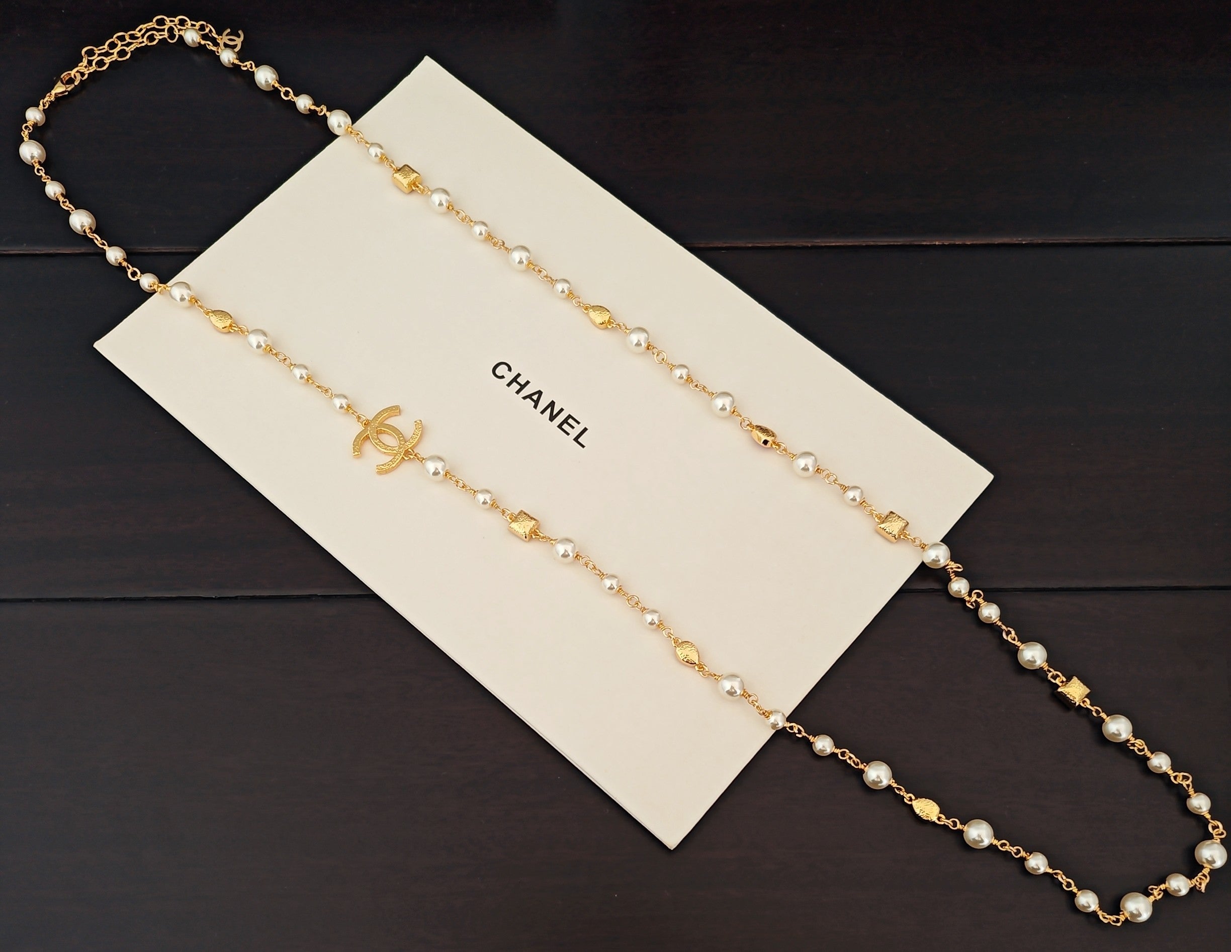 Gold-tone beaded necklace with pearl-like beads and small logo charm accents