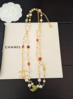 Gold-tone charm necklace set with pearl beads, dangling drops, and colorful stones