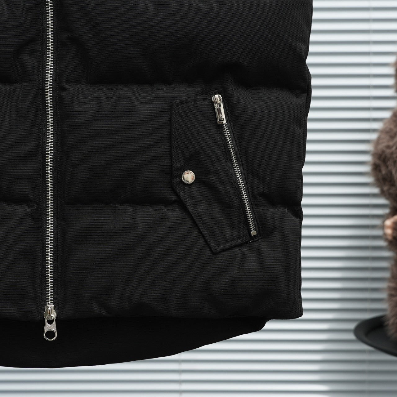 Black sleeveless puffer vest with side zip pocket and metal zipper pull
