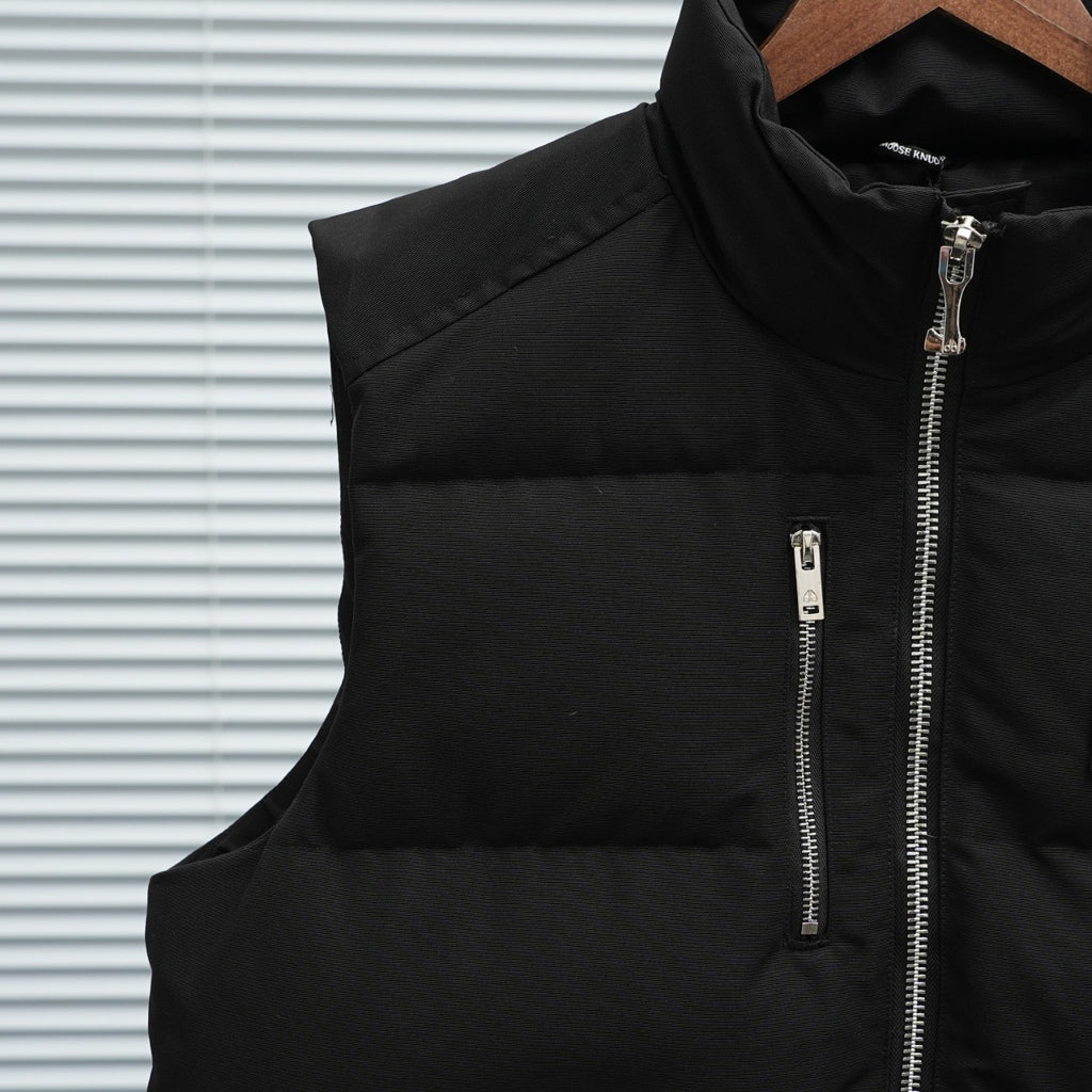 Black sleeveless puffer vest panel with central zipper and silver zip pull