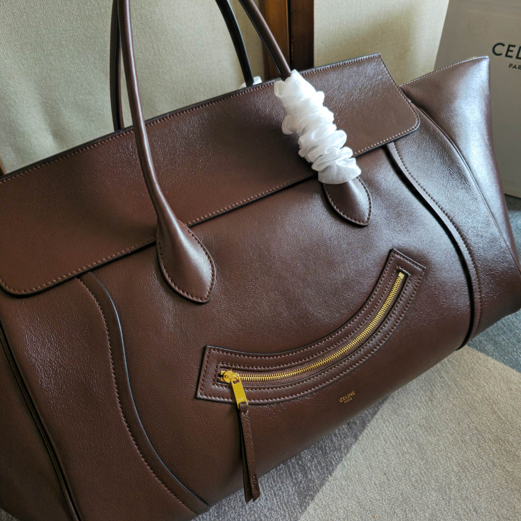 Brown leather tote bag front with gold-tone zip trim and pocket