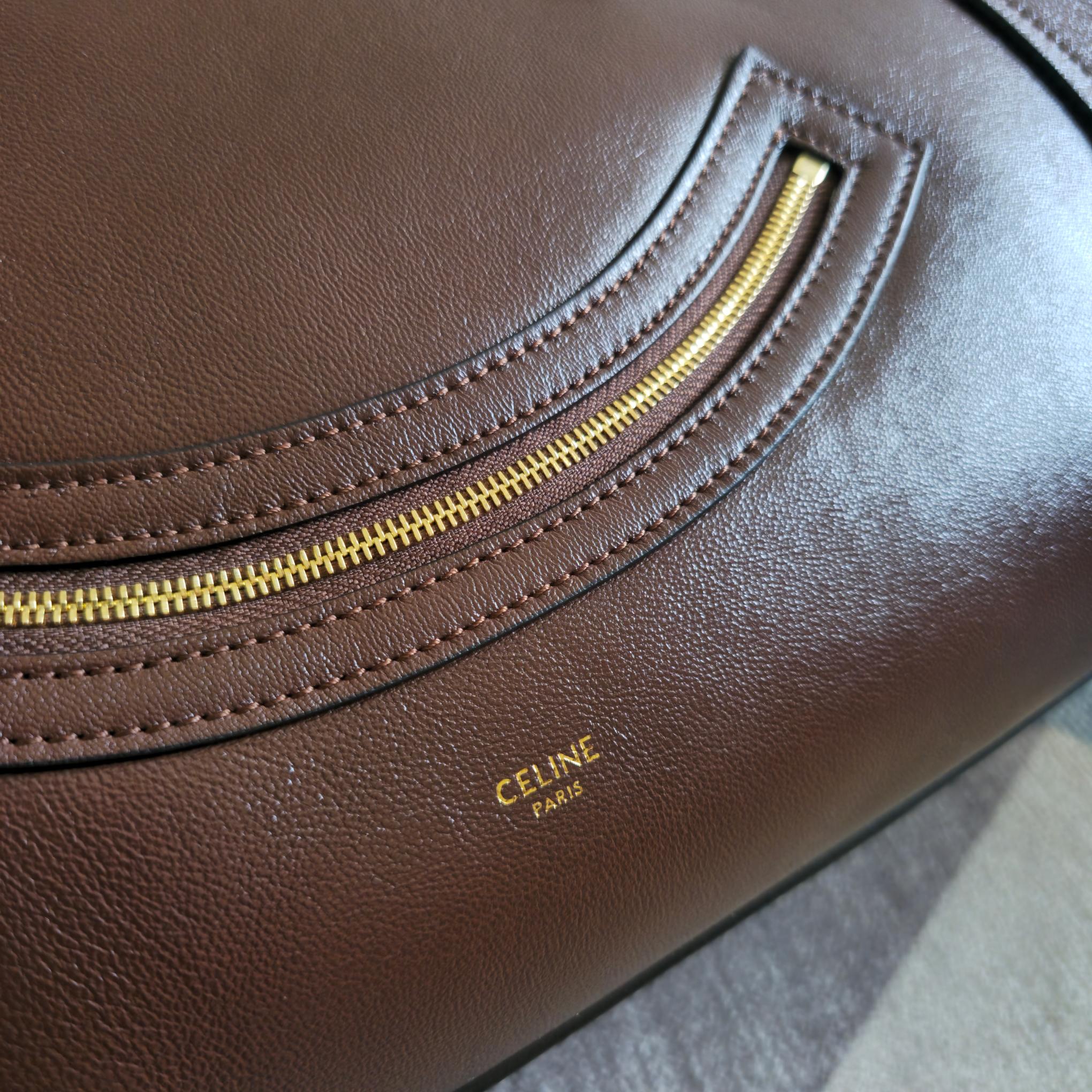 Brown leather tote bag with gold zipper track and small logo stamp