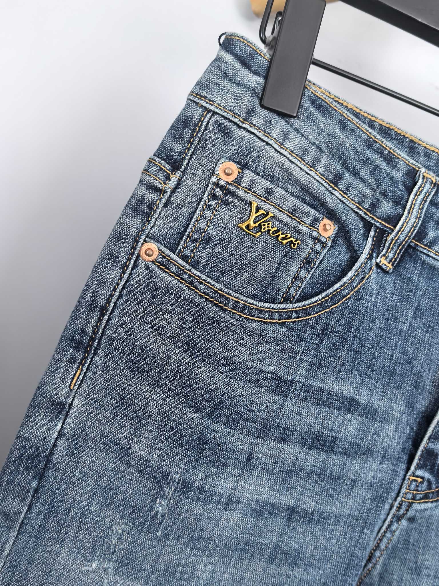 Blue denim pants front close-up with branded pocket patch and copper buttons