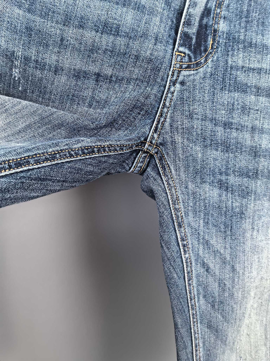 Close-up of blue denim side seam and leg with stitched cuff and pocket edge