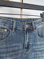 Close-up of blue denim front with button fly, belt loops, and pocket details