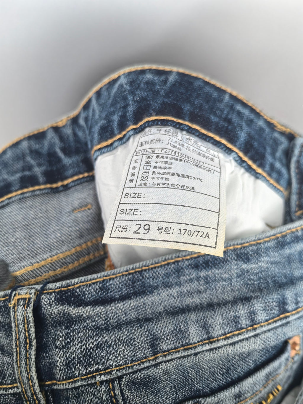Inner waistband label inside blue denim pants showing size information