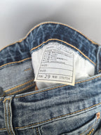 Inner waistband label inside blue denim pants showing size information
