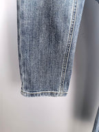 Blue denim pant leg with seam stitching and finished hem
