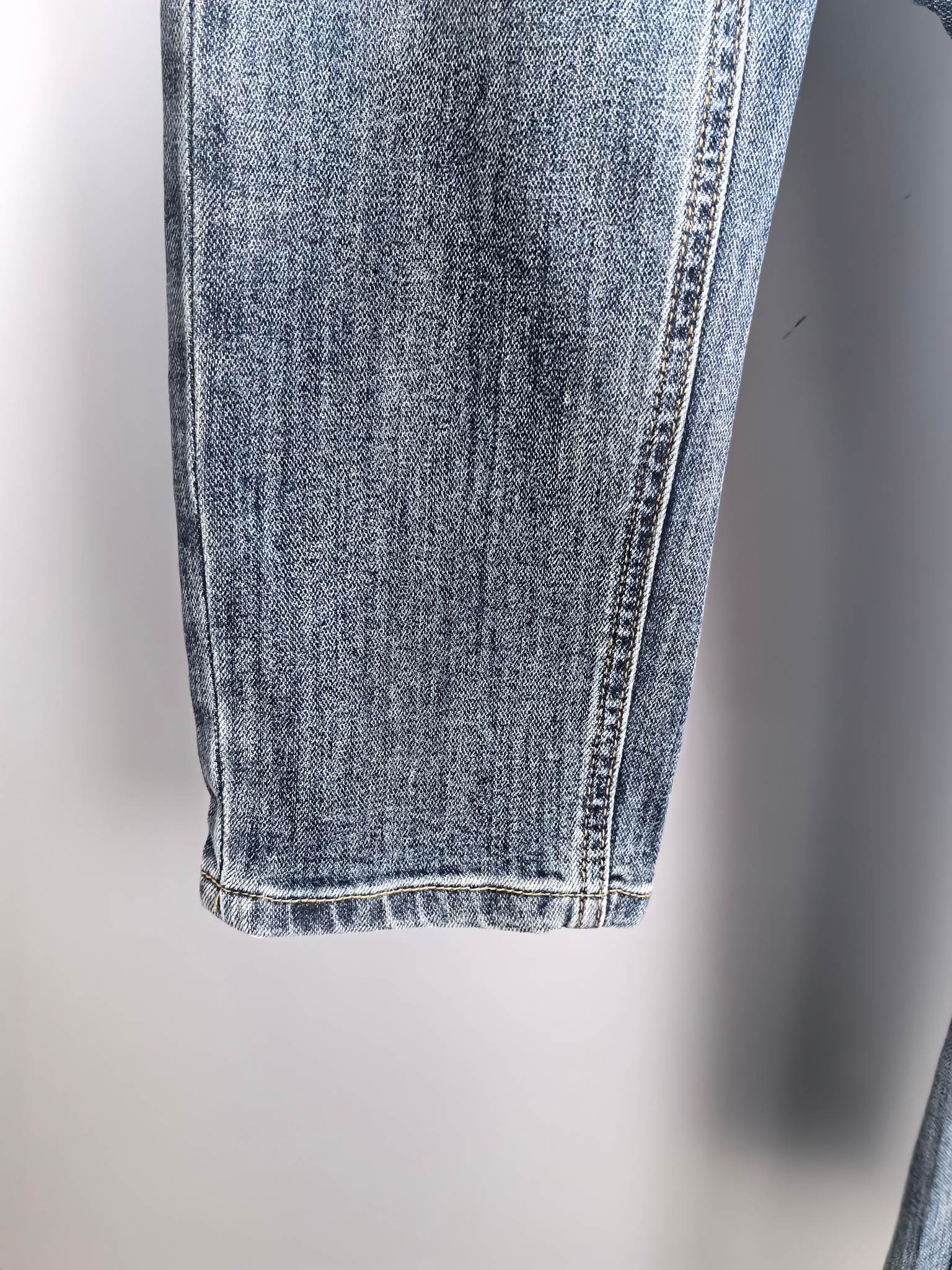 Blue denim pant leg with seam stitching and finished hem