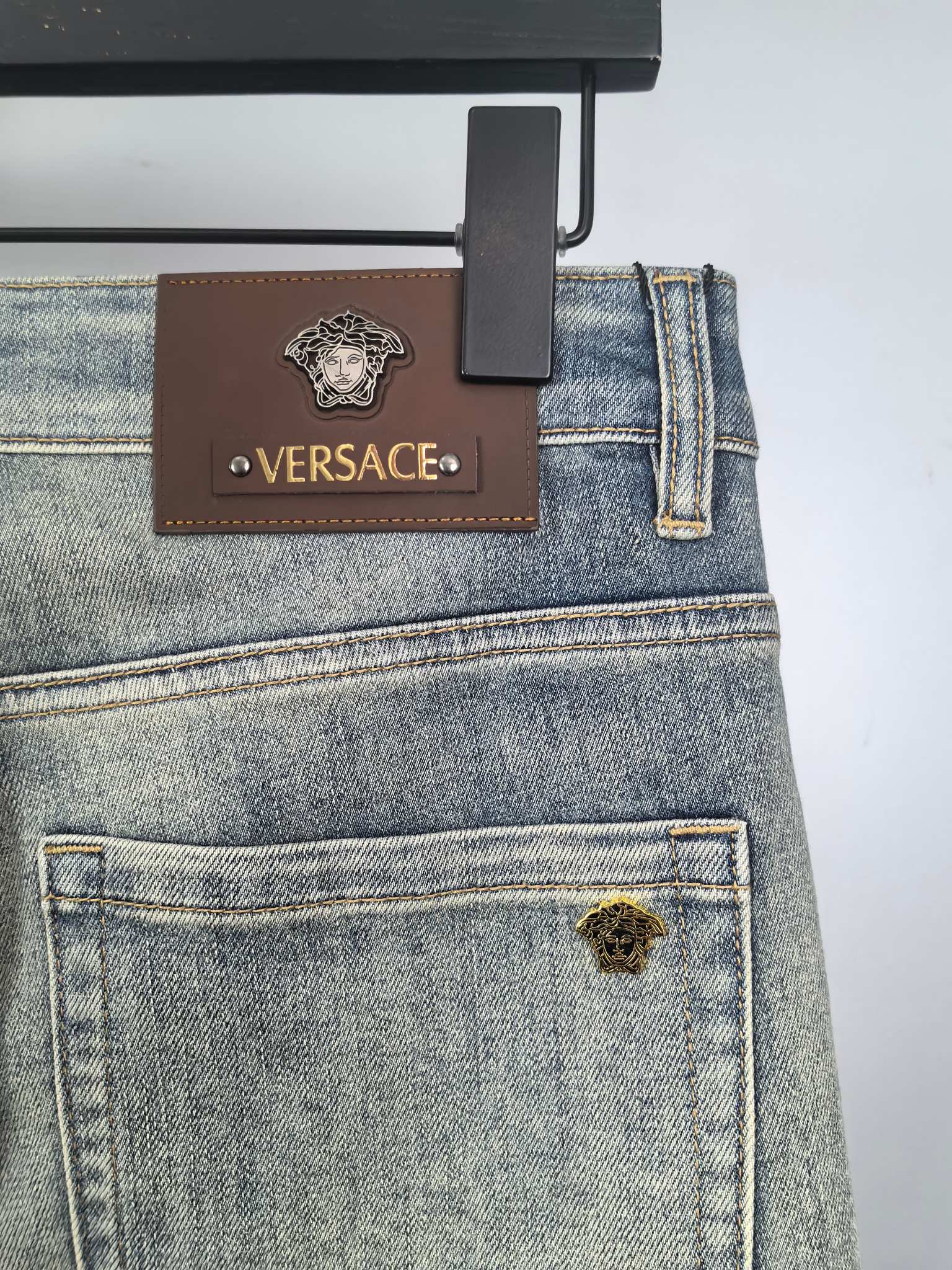 Light-blue denim jeans with leather Versace patch and logo rivets