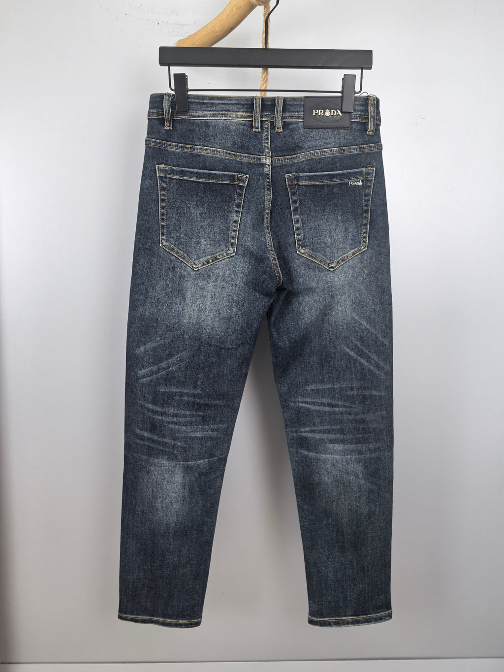 Dark blue denim pants with PRADA logo patch on waistband and front pockets.