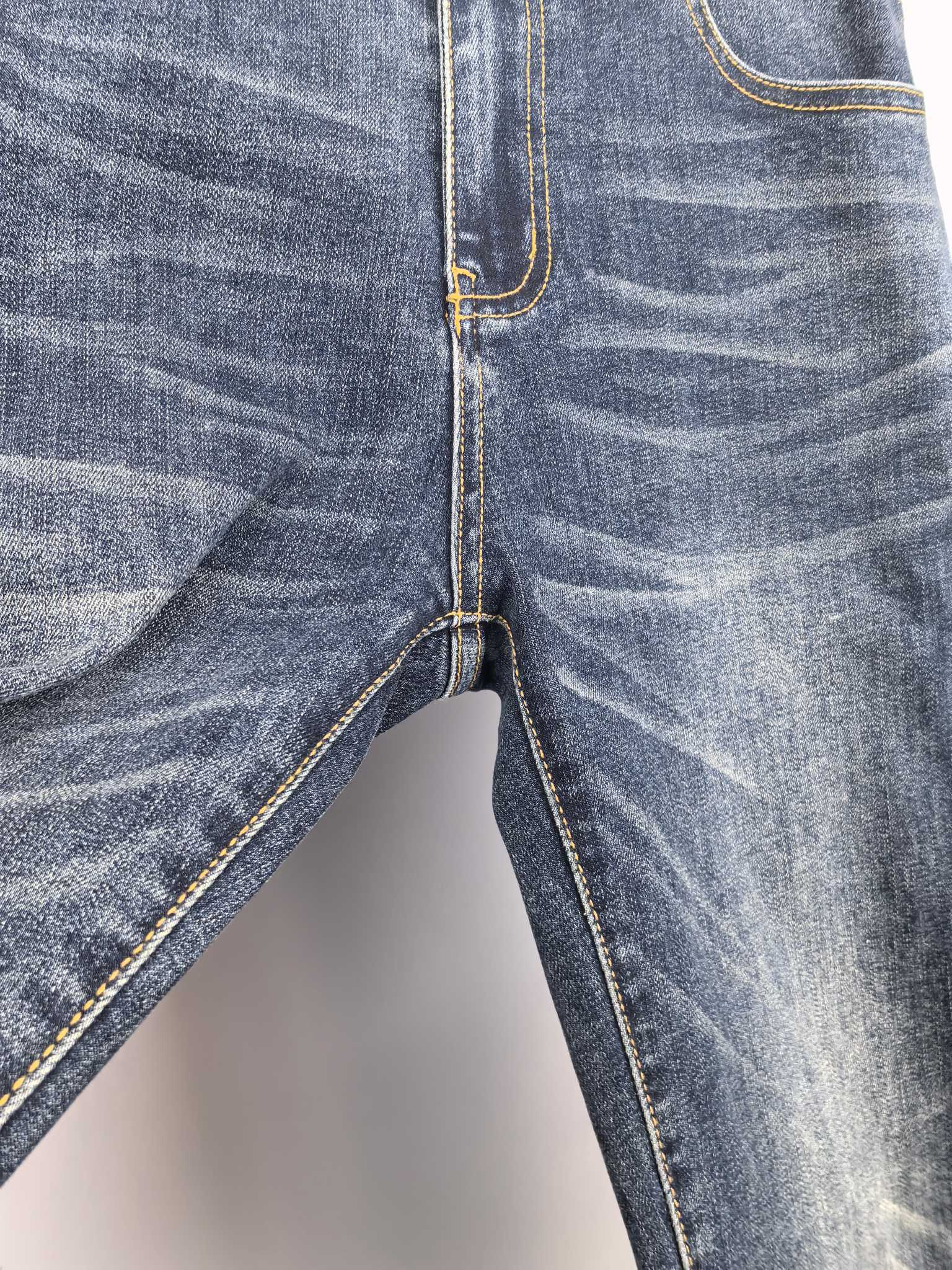 Dark blue denim pants with button fly seam and contrast yellow topstitching.