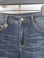 Dark blue denim waistband detail with button closure and contrast yellow stitching.