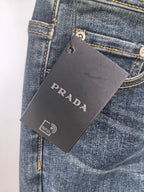 Dark blue denim jeans with PRADA hang tag and belt-loop detail.