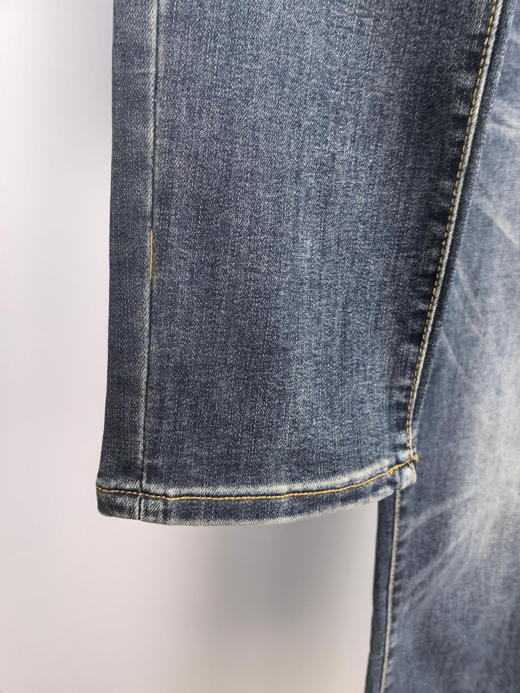 Dark blue denim pant hem with contrast yellow stitched cuff.