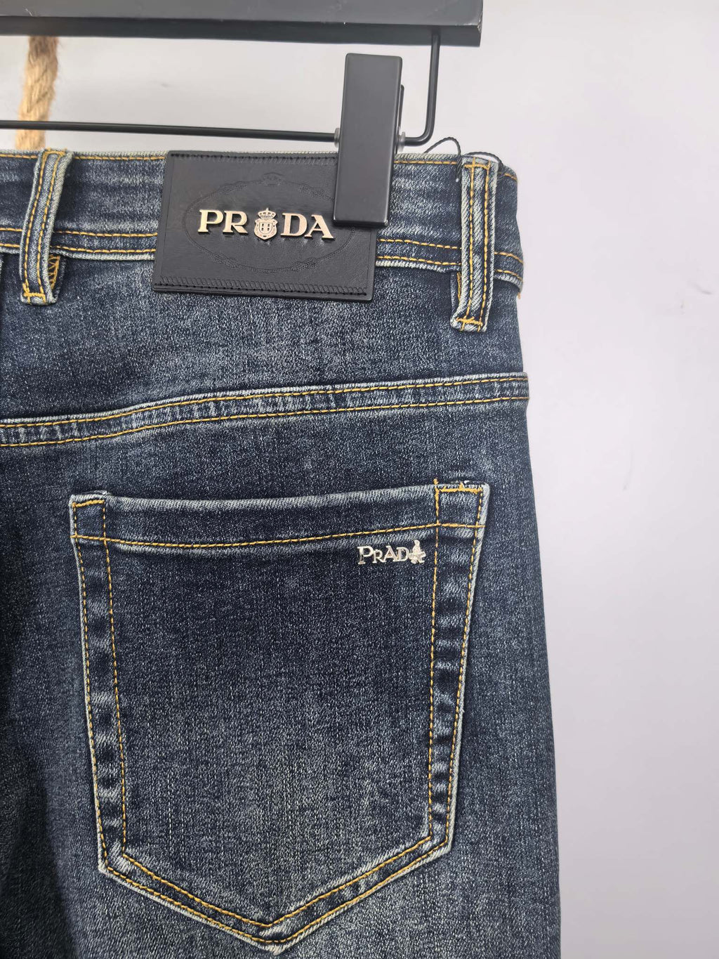Dark blue denim jeans with PRADA label on waistband and back patch pocket.