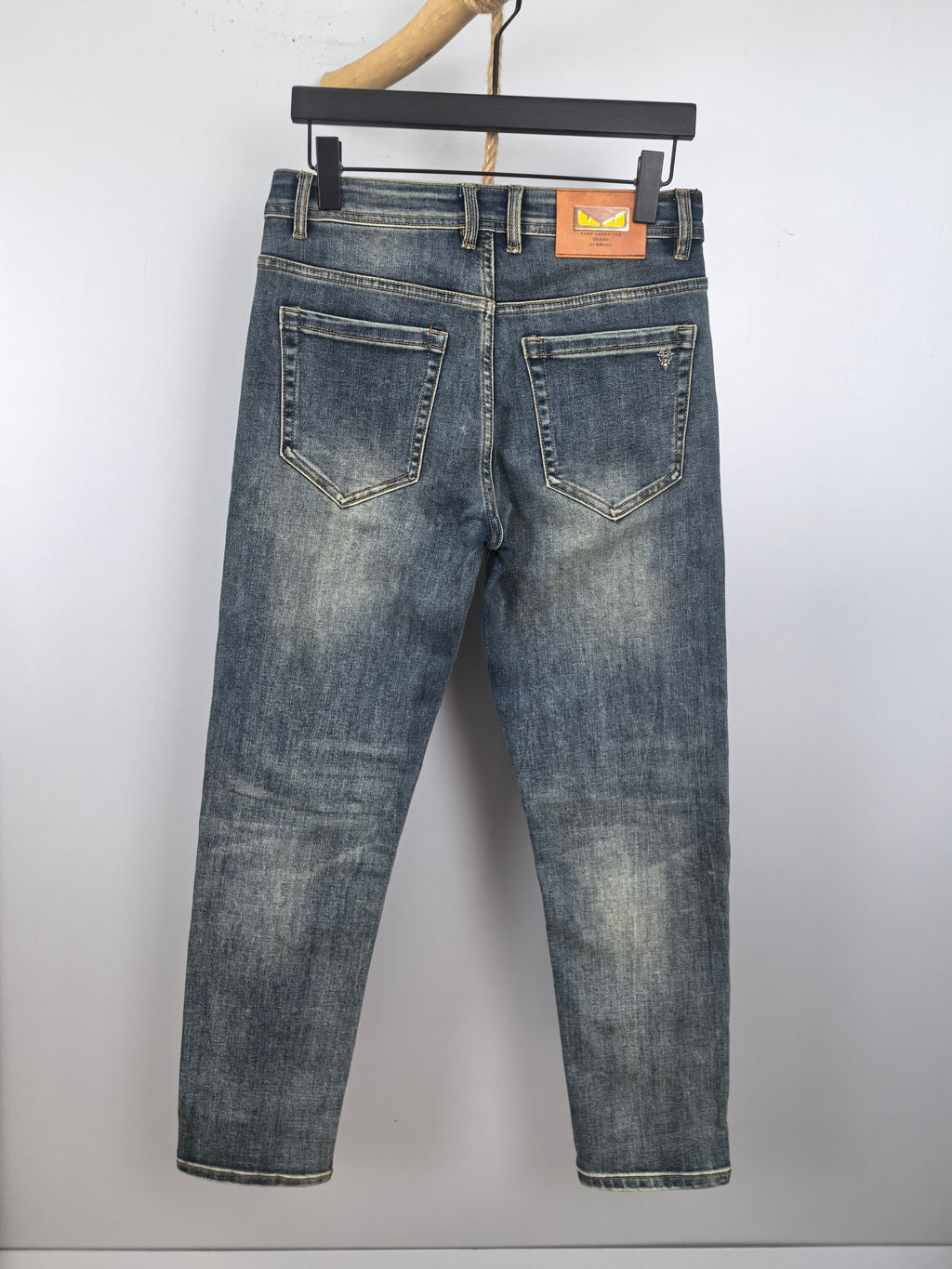 Men's blue denim pants with front pockets and waistband logo patch
