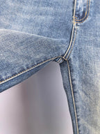 Blue denim pants side with belt loop and seam-stitch detail near knee