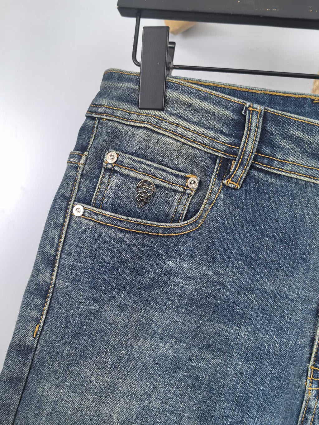 Blue denim pants front with stitched coin pocket and leather logo patch