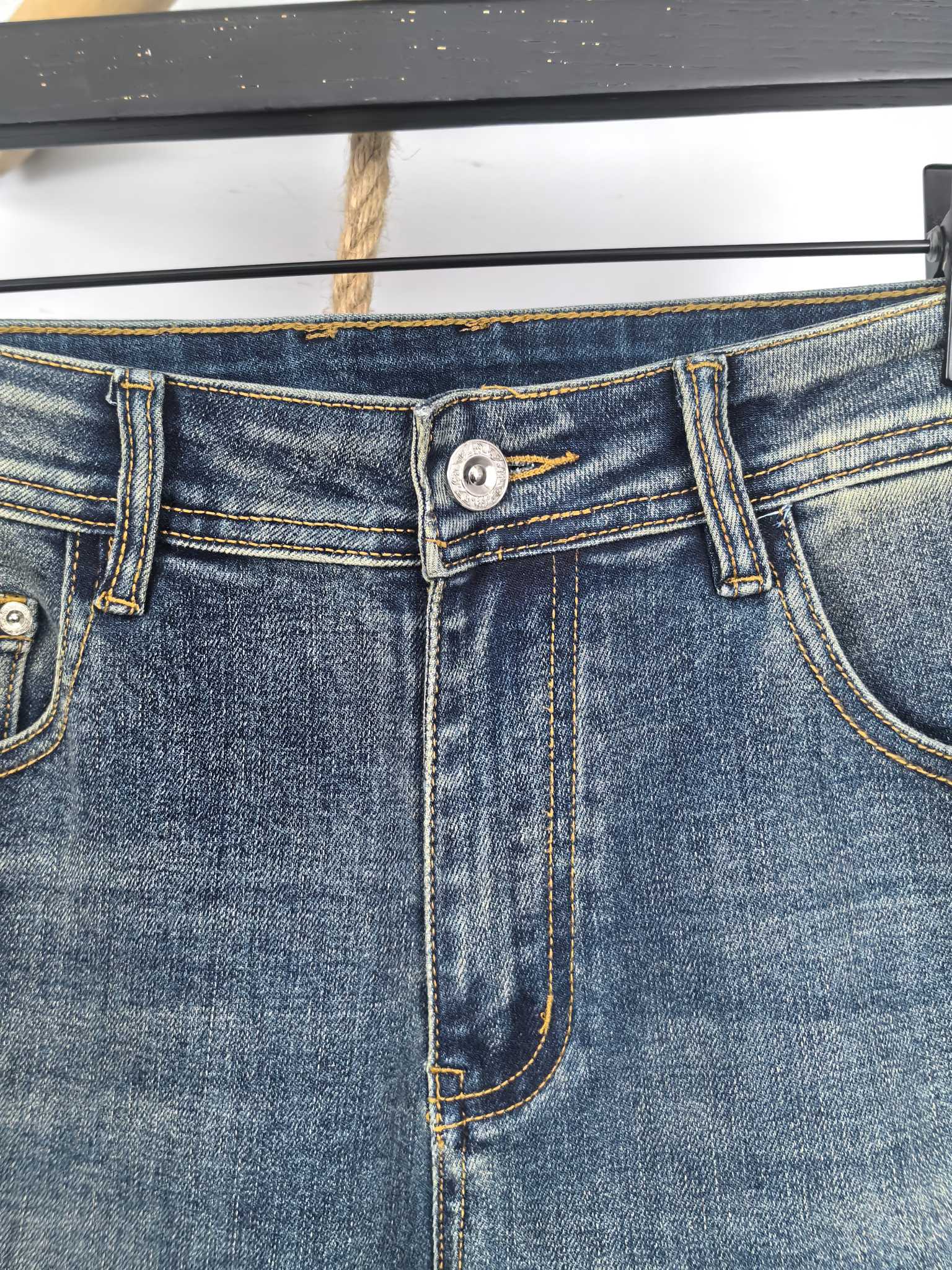Blue denim pants waistband with metal button and stitched fly detail