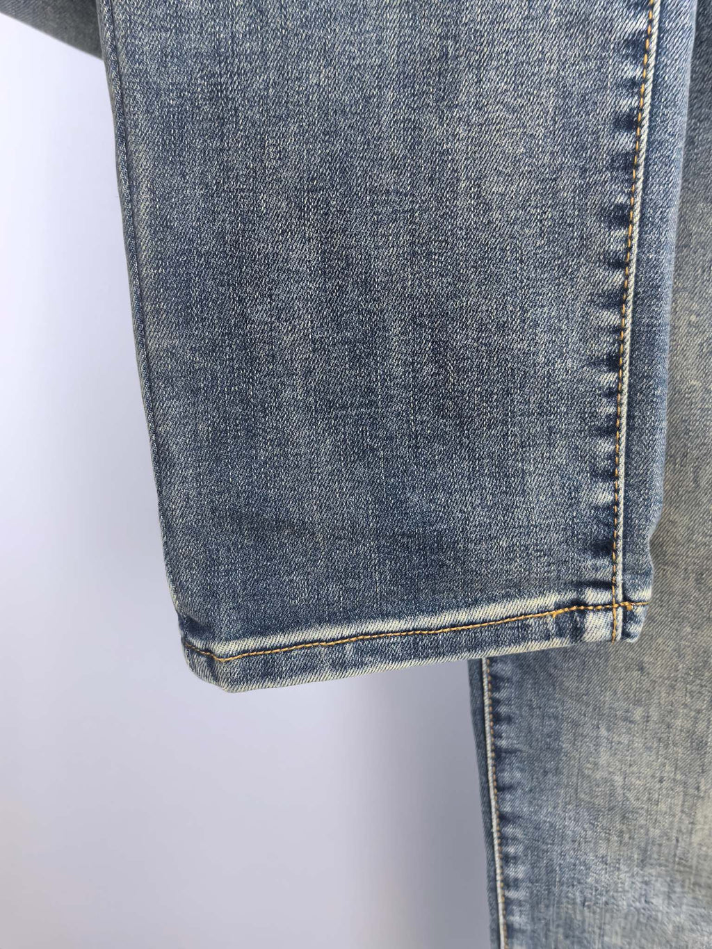 Blue denim pants hem with double stitching and vertical seam detail