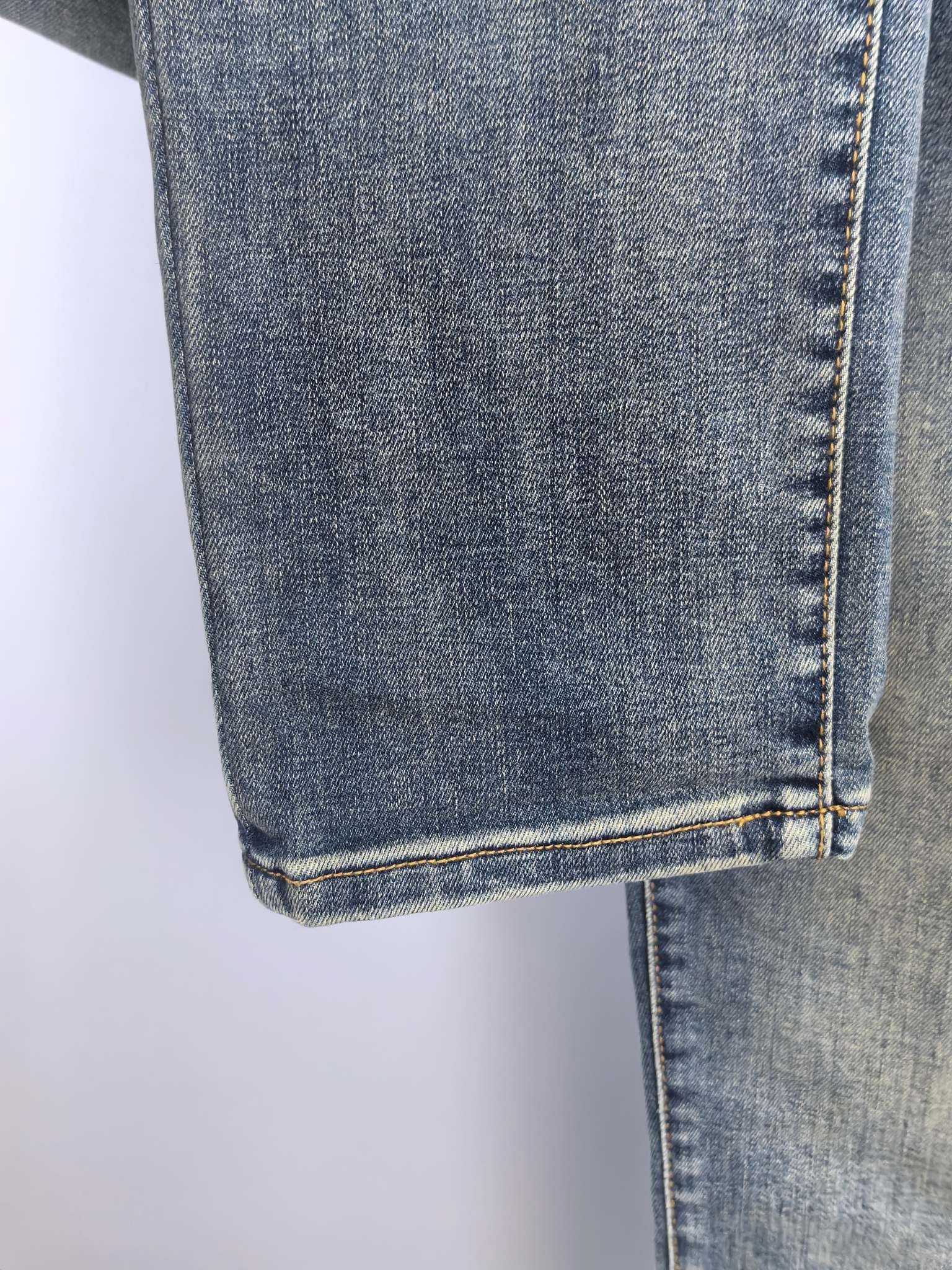Blue denim pants hem with double stitching and vertical seam detail