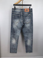 Blue denim pants with front and back pockets, stitched seams, and decorative patch