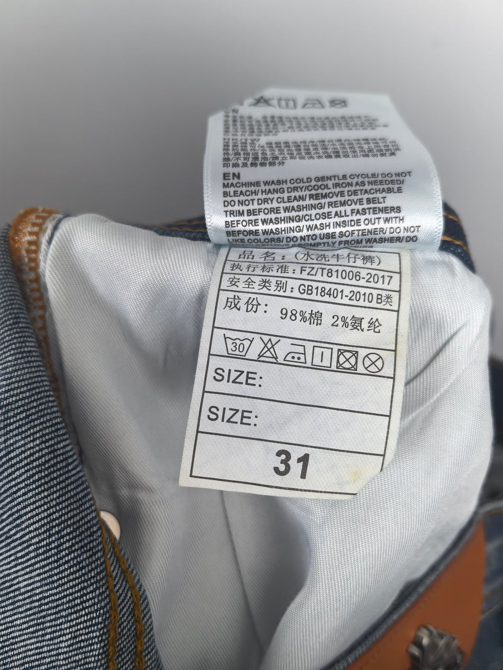 Inside label of blue denim pants with size 31 and care instructions
