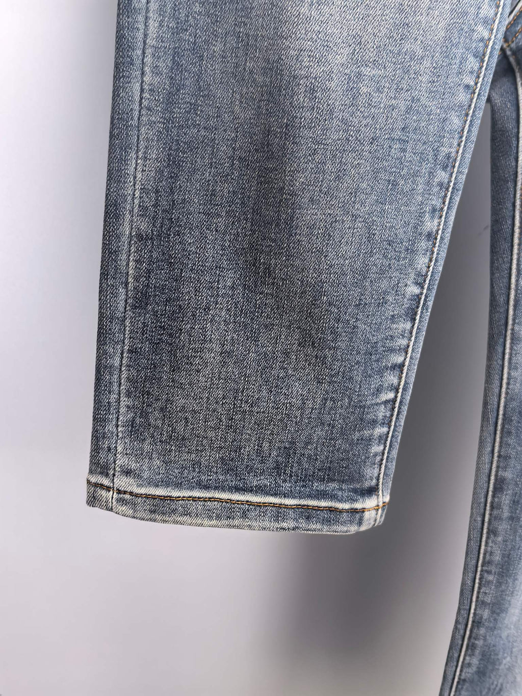 Cuffed hem and side seam of blue denim pants with light contrast stitching