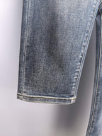 Cuffed hem and side seam of blue denim pants with light contrast stitching