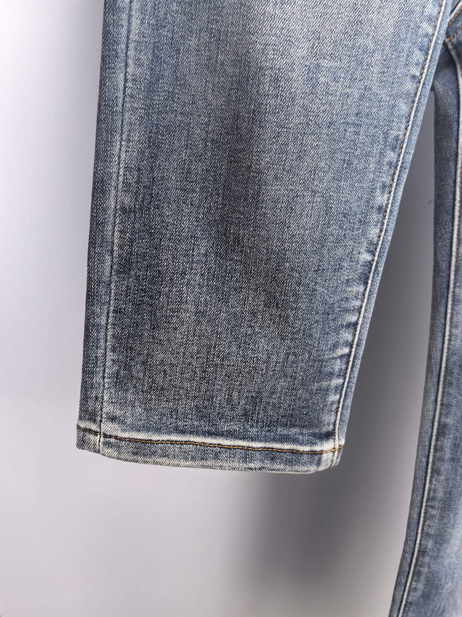 Cuffed hem and side seam of blue denim pants with light contrast stitching