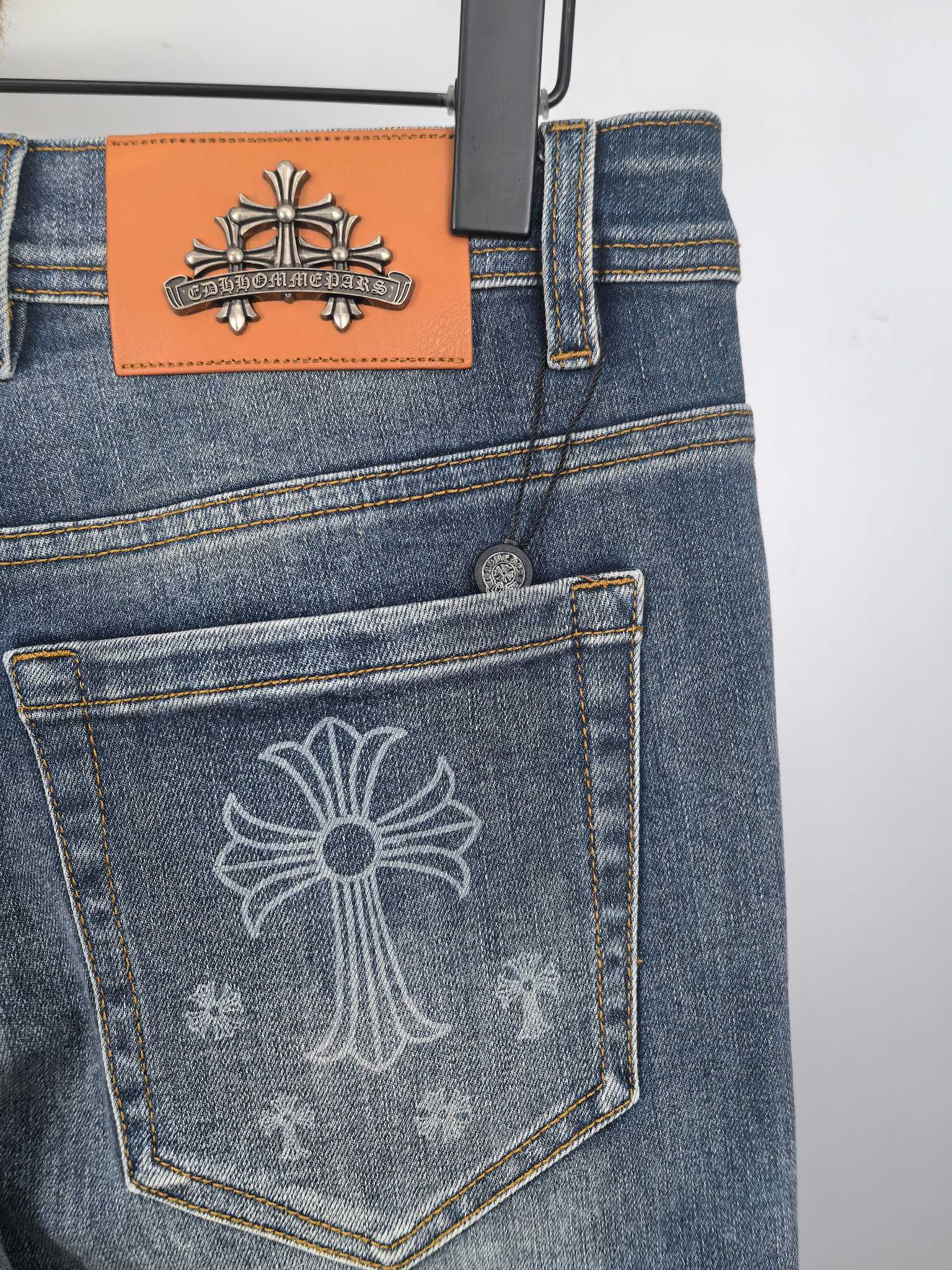 Blue denim pants back pocket with embossed cross design and orange brand patch