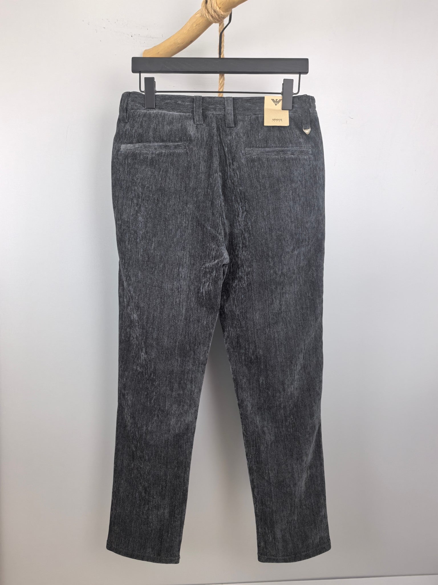 Dark charcoal trousers with belt loops and zip fly, shown from the front on a hanger.