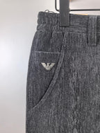 Charcoal trousers with side pocket and small triangular logo patch near the thigh.