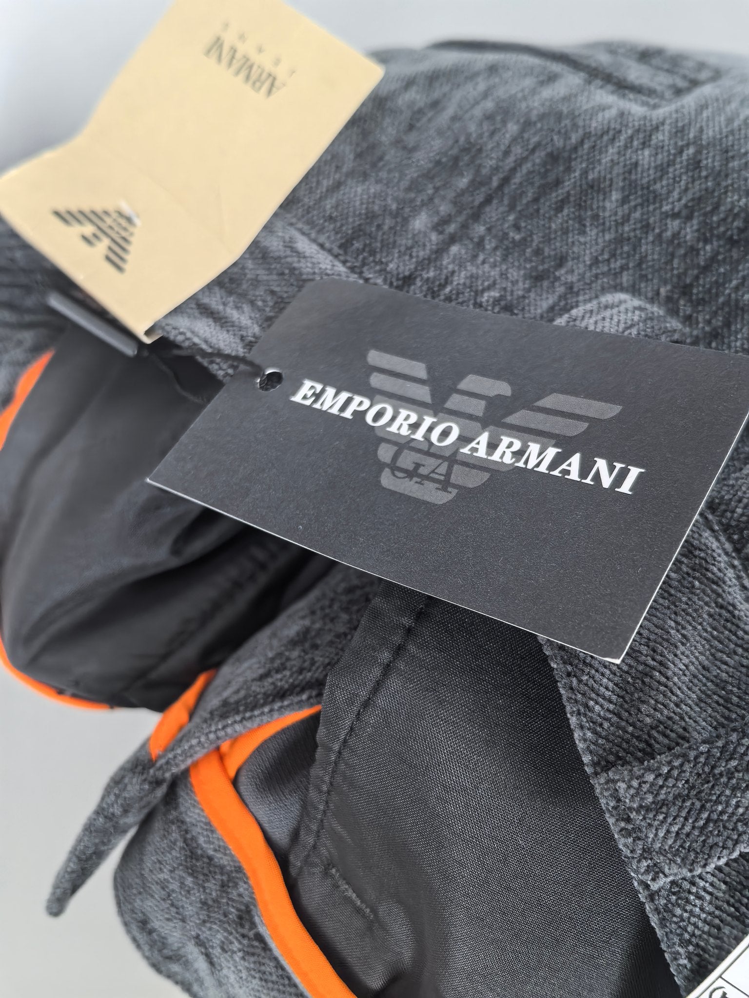 Charcoal trousers with orange inner trim and attached designer hang tags.