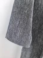 Charcoal trouser leg with textured weave and stitched hem seam, shown close-up.