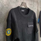 Balenciaga long-sleeve knit sweater front three-quarter view with chest pocket and crest patches
