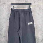 Dark sweatpants with elastic waistband and BALENCIAGA logo patch at thigh.