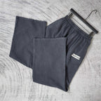 Pair of dark sweatpants laid out flat, elastic waistband and stitched pockets visible.