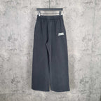 Dark drawstring sweatpants with elastic waistband, wide legs, side pocket, logo patch.
